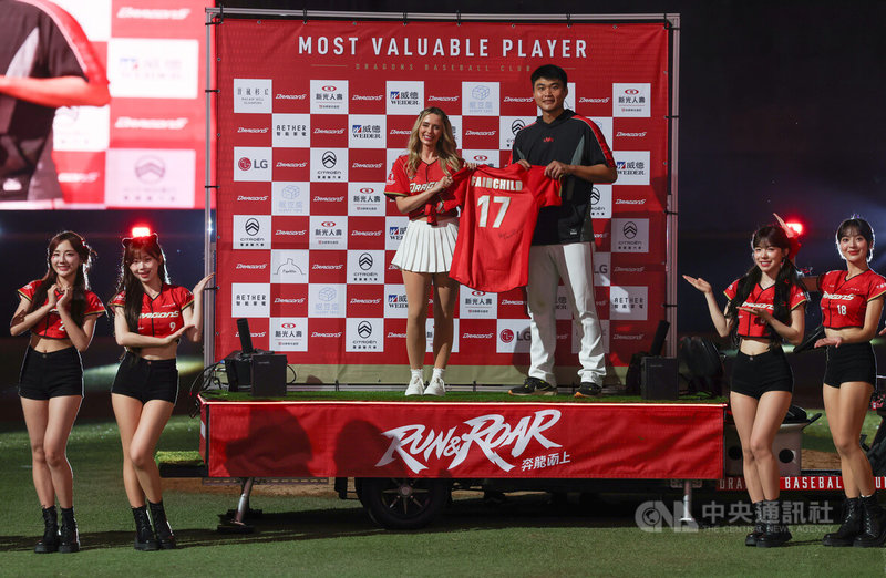中華職棒5日在天母棒球場進行台鋼雄鷹隊與味全龍隊賽事，龍隊先發投手郭郁政（後右）以68球投完6局無失分，賽後獲選單場MVP，並獲贈台美混血好手費柴德太太韓納（Hanna Fairchild）（後左）的簽名衣。中央社記者張新偉攝　115年4月5日