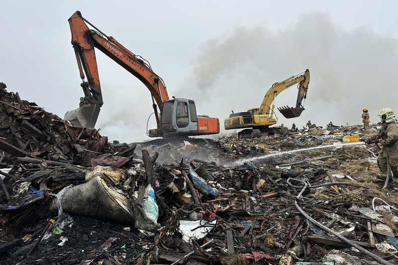 台南市學甲區掩埋場堆放的廢木材及風災廢棄物8日清晨起火,環保局調派挖土機配合消防人員作業,控制火勢。(台南市政府提供)中央社記者楊思瑞傳真 115年4月8日