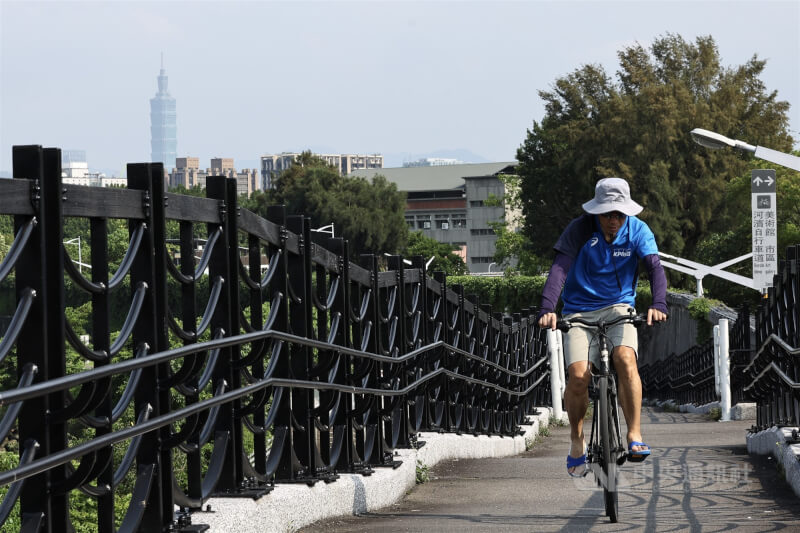 圖為民眾在台北市河濱公園戴帽子騎單車。（中央社檔案照片）