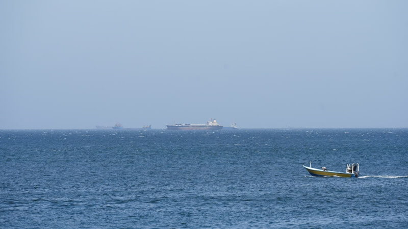 圖為8日一艘船停在荷莫茲海峽外。（路透社）