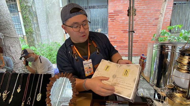 金工創作設計師黃挺瑋（圖）在「新板設計基地」文創市集中，展示自己製作的手工書，說明北歐「盧恩符文」的魅力與代表的意義。圖為黃挺瑋3月29日在「熔光金工」攤位受訪。中央社記者黃旭昇攝   115年4月11日