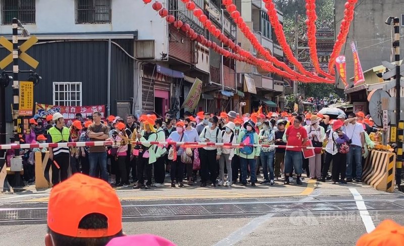 苗栗縣通霄鎮白沙屯拱天宮媽祖徒步往北港進香活動12日深夜將登轎啟程,大批香燈腳自上午陸續湧入白沙屯地區。圖為進香民眾在平交道前等待火車通過。中央社記者管瑞平攝 115年4月12日