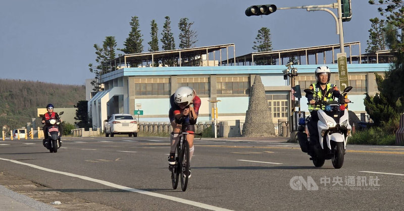 2026富邦金控IRONMAN Penghu澎湖國際鐵人三項賽12日登場,選手騎乘自行車在警車引導下前行。中央社 115年4月12日