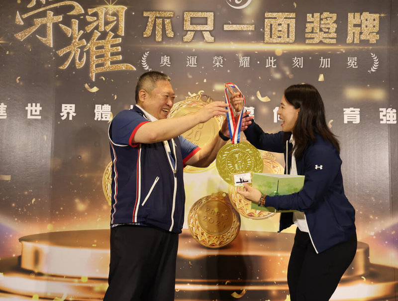 「舉重女神」郭婞淳（右）在東京奧運拿下金牌，13日獲宏道基金會頒發新台幣1000萬元獎金，她也回贈宏道基金會董事長林鴻道（左）一面自己手作的大金牌。（宏道基金會提供）中央社記者黎建忠傳真　115年4月13日
