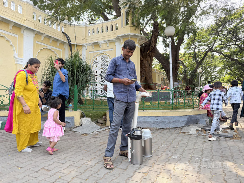印度人愛喝茶，許多地方都有流動攤販賣茶，並採現煮現賣方式銷售，但桶裝液化石油氣（LPG）因中東衝突短缺，攤商改成先將茶煮好，放進保溫瓶沿街兜售。圖為印度攤商帶保溫瓶，等待顧客上門買茶。中央社記者李晉緯新德里攝　115年4月15日