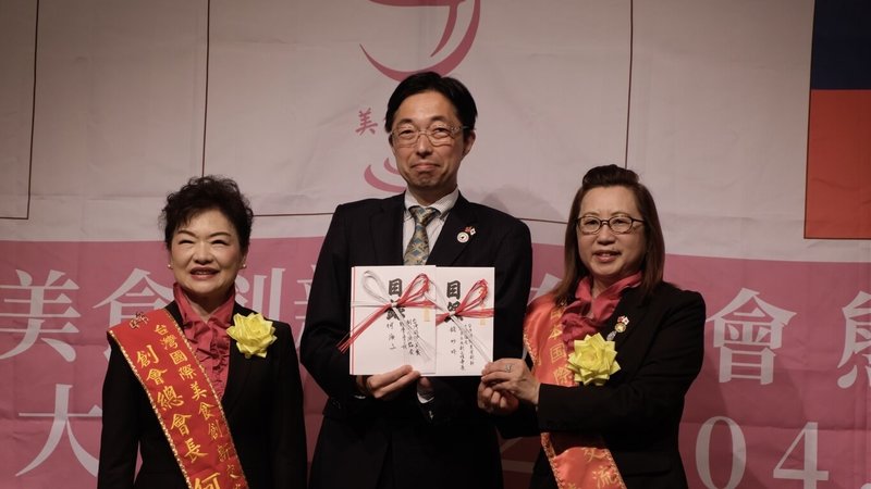 台灣國際美食創新交流協會17日在熊本台日會館舉行熊本分會成立大會，總會與熊本分會共寄贈總額達200萬日圓的點心給予熊本的兒童食堂，獲得木村敬（中）感謝，與協會總會長何淑子（左）、創會會長錢妙玲（右）合影。（熊本分會提供）中央社記者戴雅真東京傳真　115年4月17日