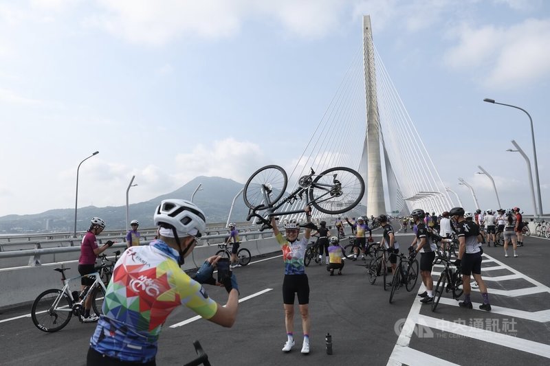 為迎接淡江大橋正式通車，交通部與新北市規畫通車前系列活動，19日舉辦自行車活動，自行車騎士騎上淡江大橋，高舉單車與淡水新地標合影留念。中央社記者吳家昇攝 115年4月19日
