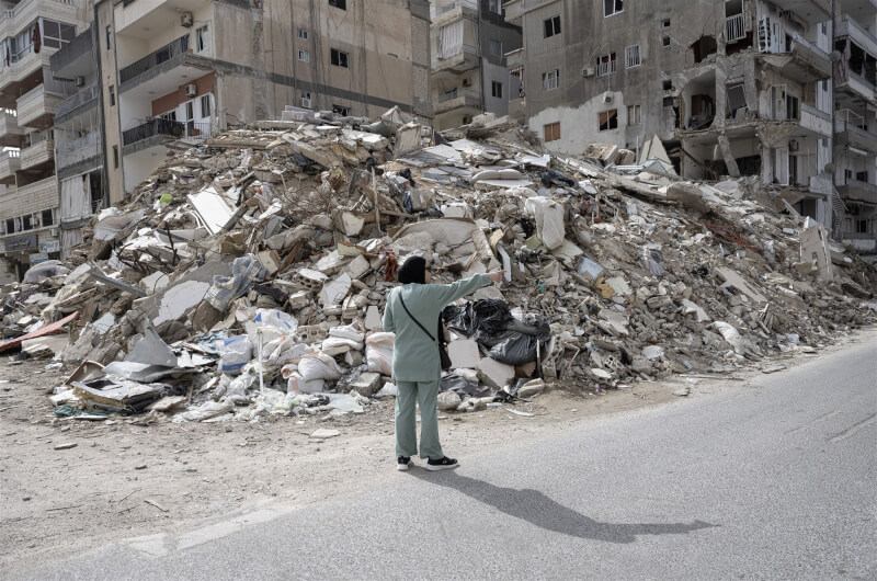 黎巴嫩南部城市泰爾的民眾19日站在被以色列摧毀的建築旁。（安納杜魯新聞社）