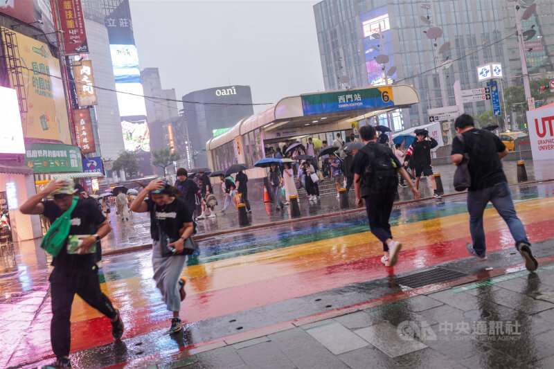 圖為台北西門町商圈23日傍晚出現雨勢，遊客快步躲雨。（中央社檔案照片）