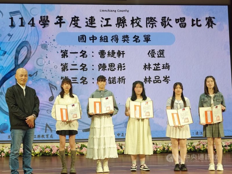 114學年度連江縣校際歌唱比賽25日在南竿鄉舉行，由縣內各校推派代表參加，縣府教育處長王禮民（左）與國中組獲獎者同台合影留念。中央社記者潘欣彤攝　115年4月25日