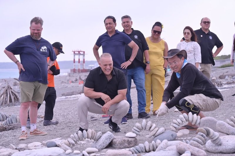 美國夏威夷州夏威夷郡長阿拉美達（左邊蹲下者）近日到訪花蓮，參觀七星潭疊石藝術創作。（花蓮縣府提供）中央社記者張祈傳真 115年4月25日