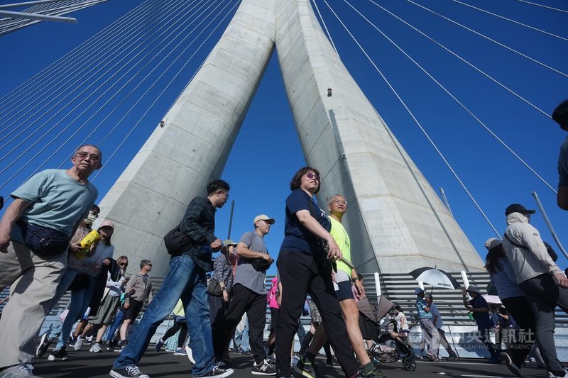淡江大橋預計5月12日通車，開幕藝術季「在一起，走上橋」大遊行26日下午熱鬧登場，參與活動民眾從漁人碼頭步向主橋塔下方。中央社記者徐肇昌攝　115年4月26日