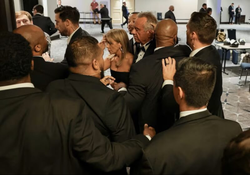 安全人員25日晚間護送美國衛生及公共服務部長小羅勃甘迺迪夫婦撤離白宮記者協會晚宴。（路透社）