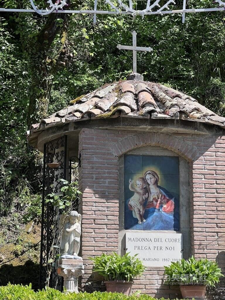 義大利傑拉諾花毯節起源是為了紀念當地教堂收藏的18世紀名畫聖母聖心像，相傳每次這幅畫要被遷走就會下雨，居民相信聖母選擇與居民同在。圖為進入小城前的聖母聖心像標示。中央社記者黃雅詩傑拉諾攝　115年4月27日