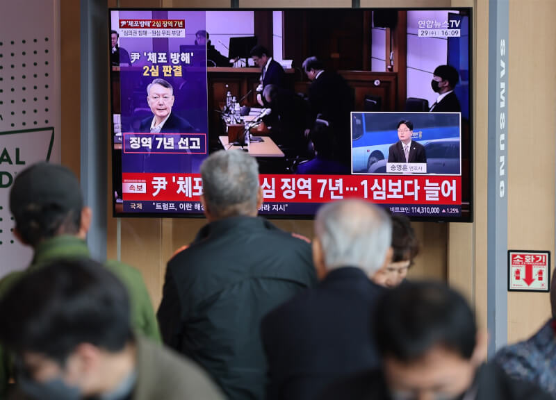 圖為韓國首爾車站候車室內民眾29日觀看前總統尹錫悅的量刑聽證會。（韓聯社）