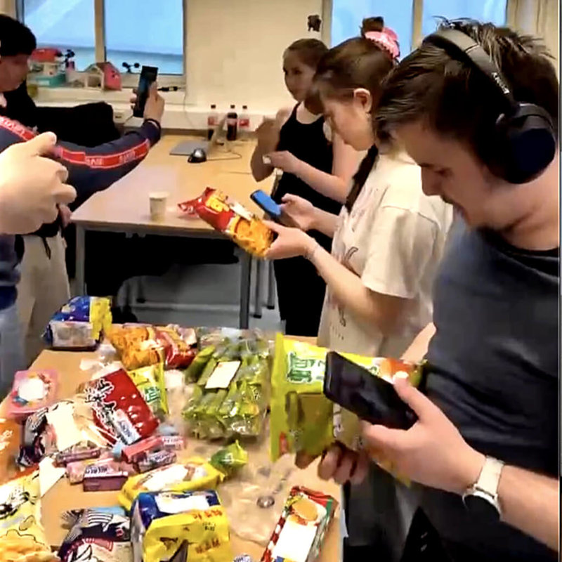 挪威瓦爾德高中的學生在教室內分享來自台灣的「零食外交」，桌上擺滿乖乖、可樂果、泡芙等台式經典點心。學生們一邊拿著手機記錄這場有趣的文化體驗，一邊品嚐台灣風味，其中草莓泡芙與可樂果最受當地青少年好評。（王湘鄉提供）中央社記者巫祈麟赫爾辛基傳真　115年5月1日