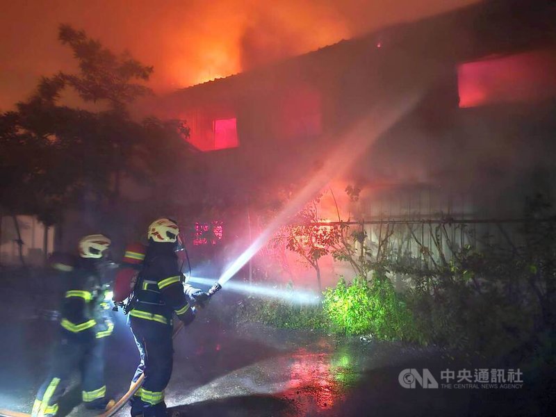 新北市八里區博物館路202巷一處2層樓鐵皮屋，1日晚間近7時有住宅冒煙，消防人員到達時，1、2樓已全面燃燒，並擴大延燒鄰宅，幸無人受困。（翻攝畫面）中央社記者黃旭昇傳真　115年5月1日