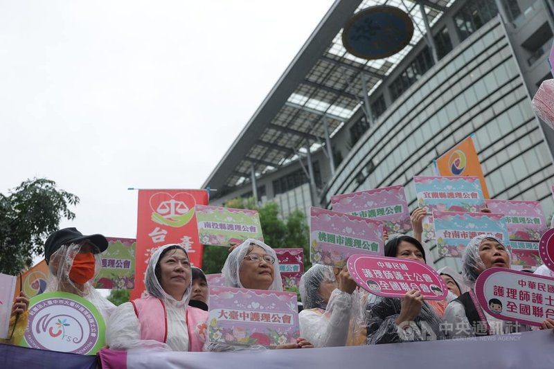 護理師護士公會全國聯合會、台灣護理產業工會5日上午動員至衛福部前抗議，現場下著大雨，護理人員身穿雨衣、手拿看板表達訴求，爭取三班護病比入法。中央社記者翁睿坤攝　115年5月5日