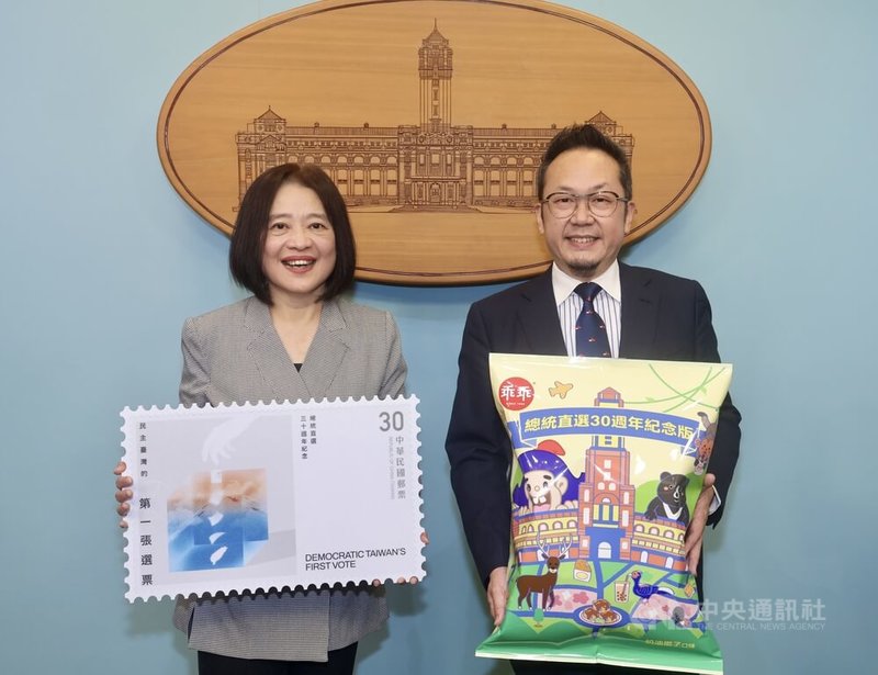 總統府7日舉行「總統直選30週年系列活動」記者會，邀請民眾共同見證台灣民主發展歷程。圖為中華郵政經營設計策略委員會副主委康嘉芳（左）、文總祕書長李厚慶（右）持周邊紀念品合影。中央社記者張皓安攝　115年5月7日