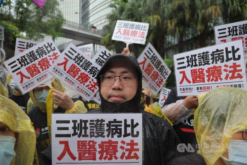 多位護理人員5日在衛福部前手拿看板表達「三班護病比入醫療法」訴求。（中央社檔案照片）