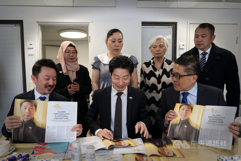 駐芬蘭代表林昶佐（前中）贈台商刊登其專訪的百年政經雜誌「芬蘭畫報」，並以老派鋼筆逐一簽名。中央社記者巫祈麟赫爾辛基攝　115年5月12日
