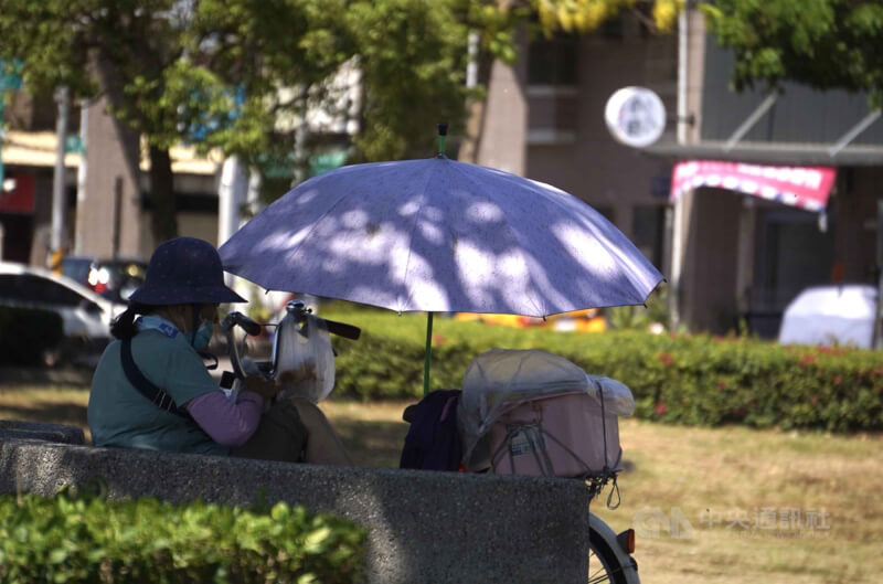 中央氣象署12日針對台南、屏東發布高溫資訊，注意氣溫達局部攝氏36度以上。圖為高雄民眾撐傘遮陽在五甲公園樹蔭下乘涼。（中央社檔案照片）