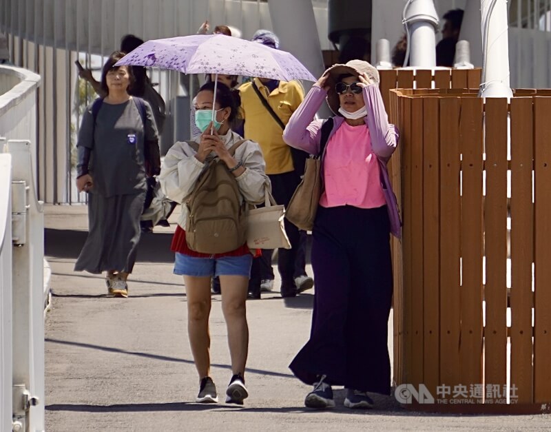 圖為午後赴高雄駁二藝術特區周邊遊憩民眾戴起墨鏡防曬、撐傘遮陽。（中央社檔案照片）