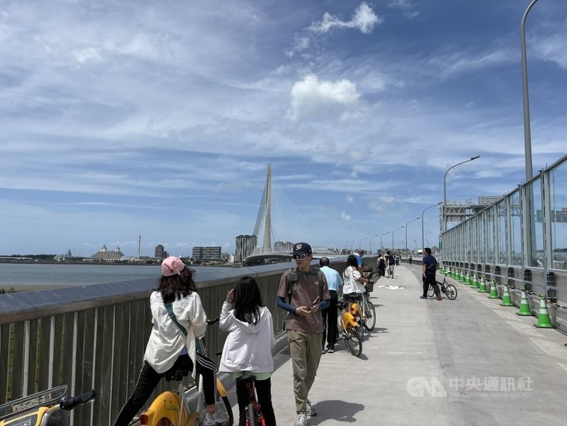 淡江大橋通車後首個週末，許多民眾16日下午把握好天氣騎腳踏車或步行上橋，沿途不時停下欣賞風景。中央社記者曹亞沿攝 115年5月16日