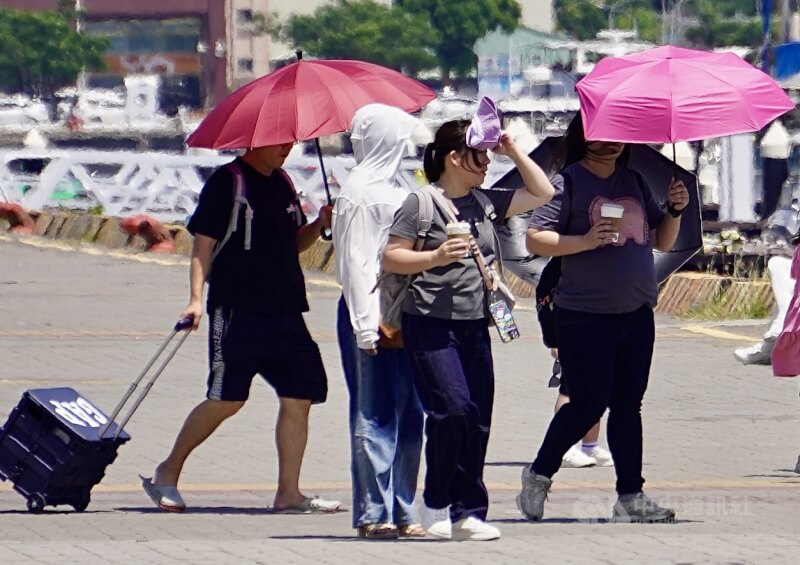 圖為高雄駁二藝術特區周邊遊憩民眾披上薄外套遮擋烈陽、撐傘防曬。（中央社檔案照片）