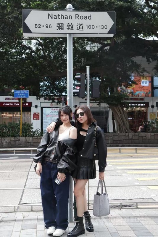 香港不少道路是以前英國官員命名，這些道路名稱至今吸引不少旅客好奇，成為他們的打卡熱點；圖為兩名陸客在彌敦道（尖沙咀段）路牌拍攝，這條道路是以第13任港督彌敦爵士命名。中央社記者張謙香港攝 115年5月21日
