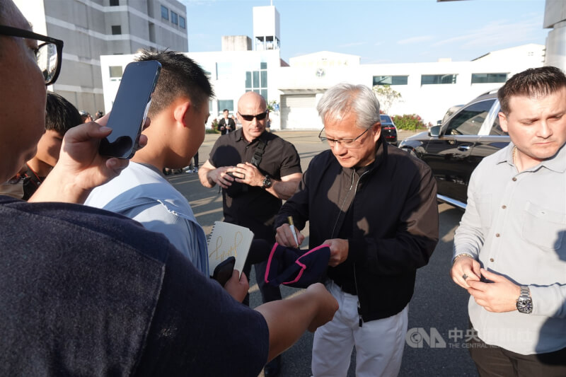 輝達執行長黃仁勳(右2)23日下午搭乘私人專機抵台,在松山機場商務中心外幫熱情守候的民眾簽名。中央社記者吳書緯攝 115年5月23日