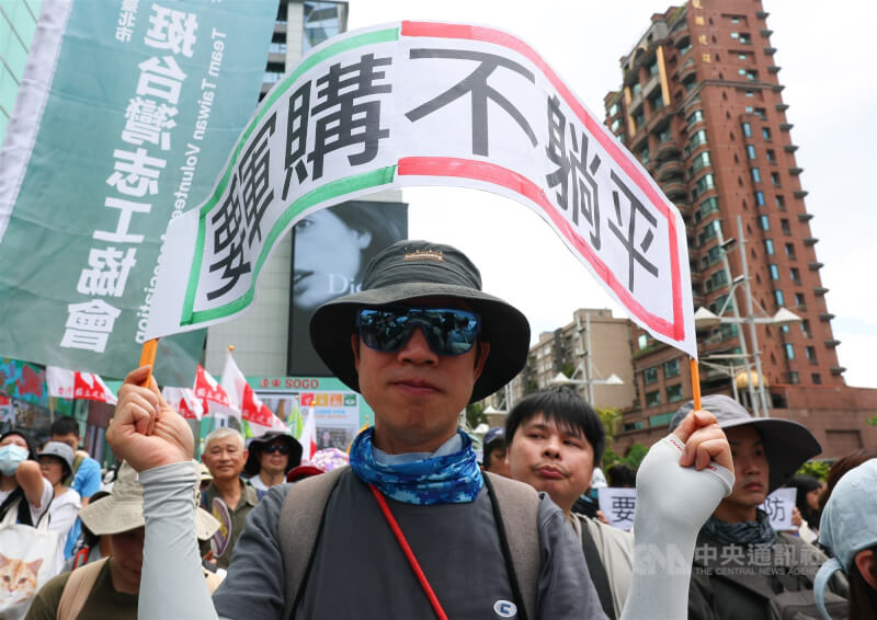 台灣公民陣線、台灣經濟民主連合等民團23日在台北舉行「真和平,要國防」523遊行,與會民眾高舉「要軍購不躺平」標語表訴求。中央社記者謝佳璋攝 115年5月23日
