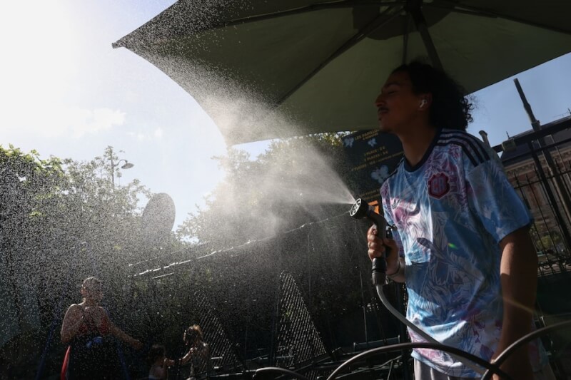 法國巴黎25日氣溫高達攝氏35度，民眾噴水降溫。（路透社）