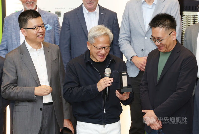 輝達執行長黃仁勳(前中)29日在南港展覽館2館出席輝達AI Factory MGX Ecosystem Ceremony,手持迷你版MGX機櫃架構。中央社記者張新偉攝 115年5月29日