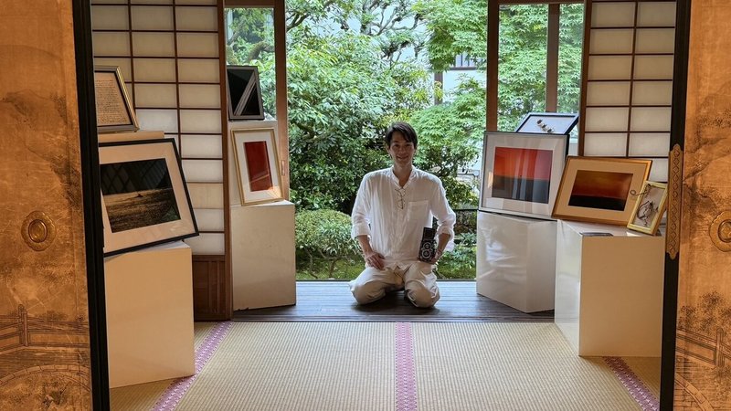 以「色彩」為題的Colors特展27日起在日本京都泉涌寺登場，展覽集結台灣藝術家蔡爾平、長年在京都創作的台灣陶藝家張義明，以及旅居台灣的日本攝影藝術家岡本孝3人作品，透過陶藝、攝影與複合媒材等不同形式，共同詮釋人與自然之間的色彩語言。圖為岡本孝與作品合影。（台灣國王十字藝術社提供）中央社記者戴雅真東京傳真　115年5月29日