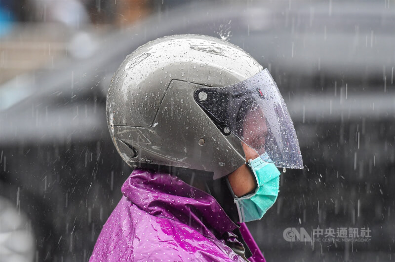圖為台北市區騎乘機車的民眾穿上雨衣遮擋雨勢。（中央社檔案照片）