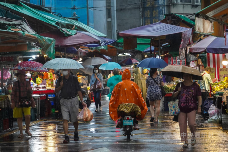 圖為台北市信義區午後雨勢漸大，民眾撐傘在傳統市場採買。（中央社檔案照片）