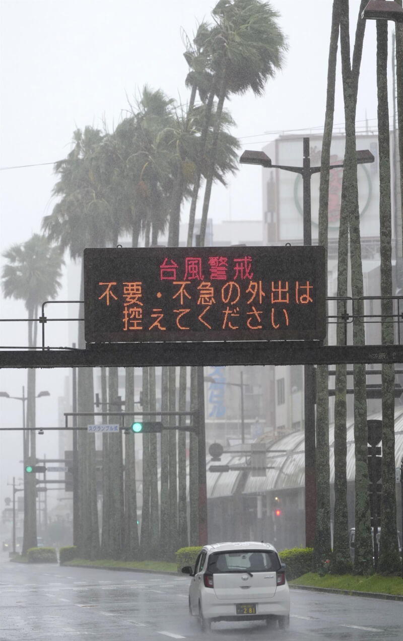 颱風薔蜜持續北上，2日晚間接近日本九州南部，宮崎市下午風雨已強，道路看板提示用路人警戒颱風。（共同社）
