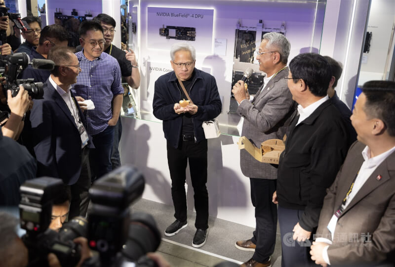2026 COMPUTEX（台北國際電腦展）3日持續在台北南港展覽館進行，輝達（NVIDIA）執行長黃仁勳（中）前往鴻海等台廠供應鏈展位參觀，並品嚐紅豆餅。中央社記者趙世勳攝　115年6月3日