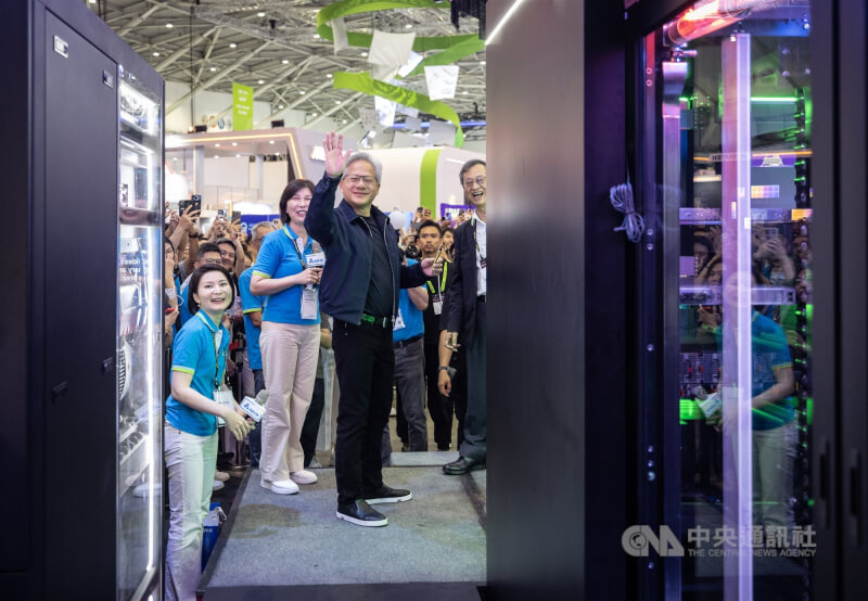 2026 COMPUTEX(台北國際電腦展)持續在台北南港展覽館進行,輝達(NVIDIA)執行長黃仁勳3日前往研華、鴻海、台達電等供應鏈廠商展位相挺。圖為黃仁勳(中)抵達台達電展位向周圍粉絲揮手致意。中央社記者趙世勳攝 115年6月3日