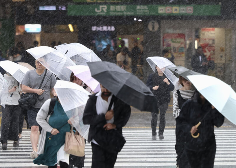 颱風「薔蜜」3日凌晨在日本和歌山縣南部登陸後，挾豪雨襲東京首都圈。圖為東京新宿站前行人撐傘過馬路。（共同社）