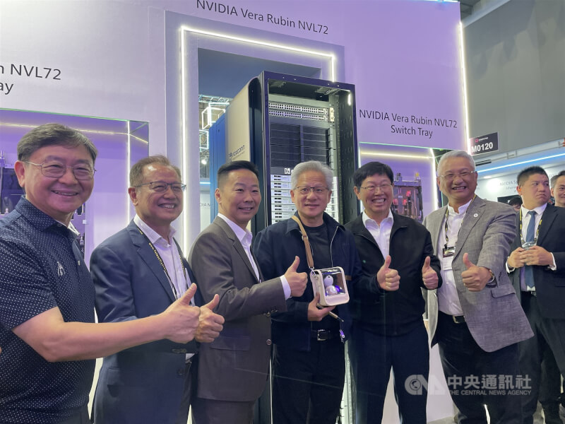 輝達（NVIDIA）執行長黃仁勳（左4）於3日中午參觀鴻海COMPUTEX展區，帶著鴻海贈送的夏普人工智慧AI陪伴型機器人Poketomo合影。中央社記者鍾榮峰攝　115年6月3日