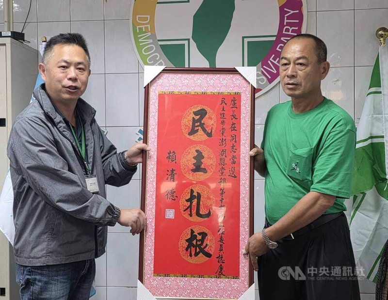 民進黨澎湖縣黨部主委交接5日在縣黨部舉行，中央黨部專員鄭凱元（左）代表身兼黨主席的總統賴清德致贈「民主扎根」賀匾給再度回鍋的主委盧長在（右）。中央社  115年6月5日
