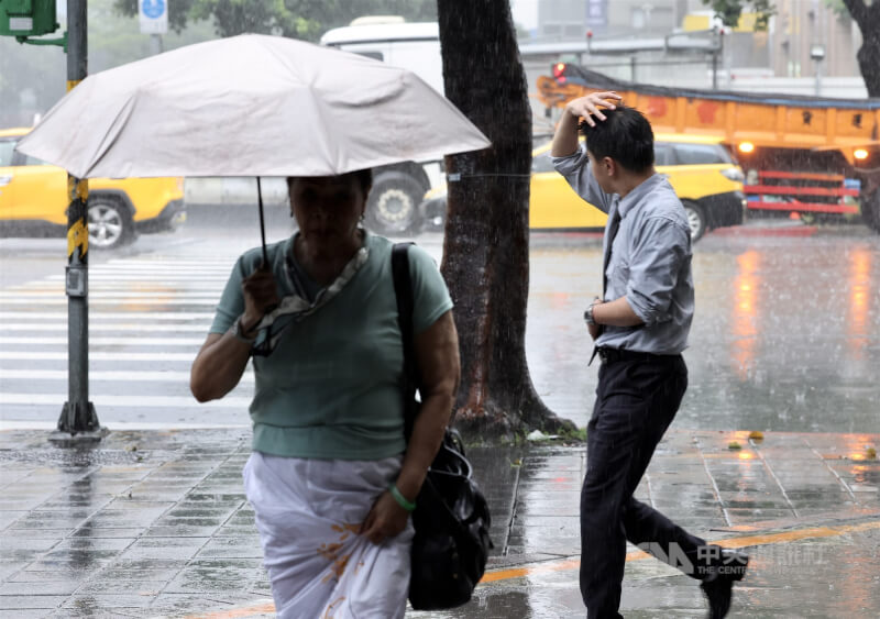 圖為8日北市中山區民眾沒帶雨傘,用手遮擋雨勢。中央社記者張皓安攝 115年6月8日