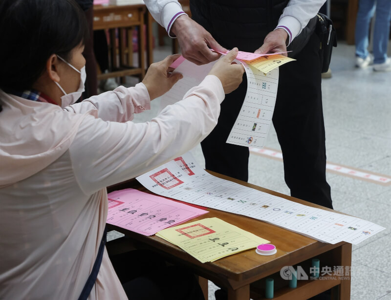 圖為選務人員協助民眾領取總統副總統選票、區域或原住民立委選票及政黨票。(中央社檔案照片)