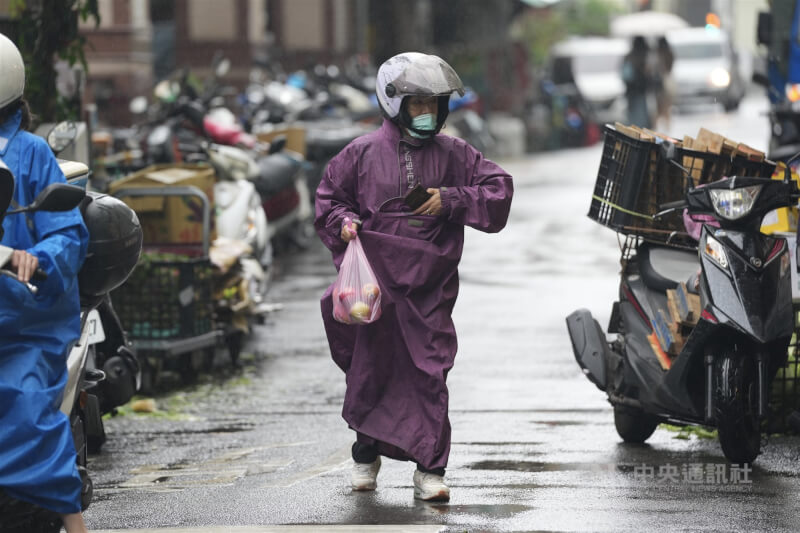 圖為民眾穿著雨衣在台北市北投市場外攤採買蔬果。（中央社檔案照片）