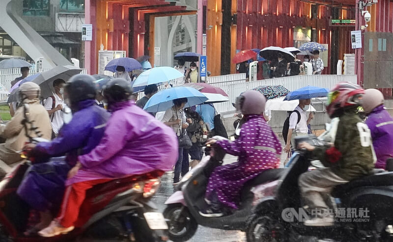 圖為高雄市前鎮區降雨，民眾撐傘、騎士穿雨衣往來街頭。（中央社檔案照片）