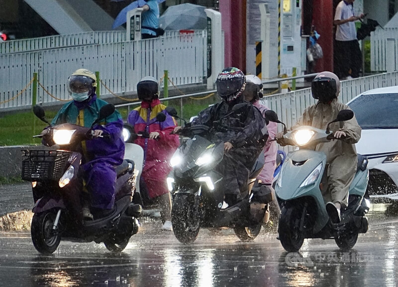 高雄市前鎮區街頭機車騎士穿好雨衣在雨中騎行。（中央社檔案照片）