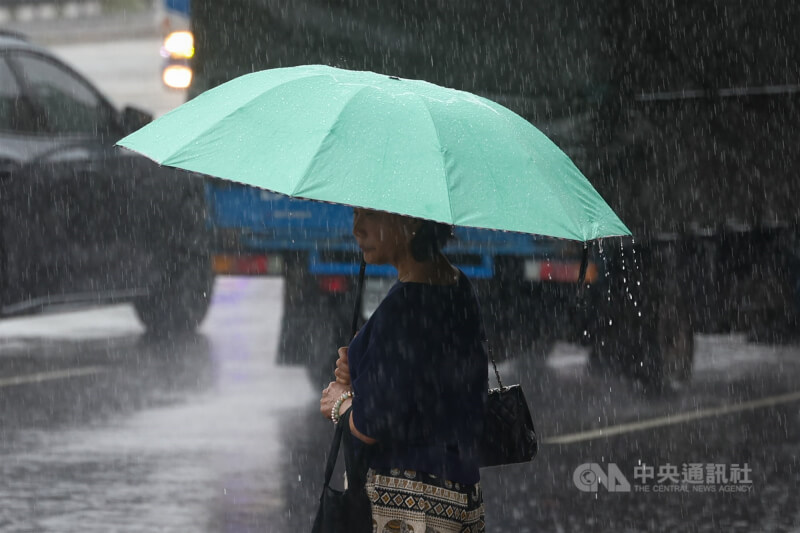 圖為新北市土城區民眾撐傘在雨中等候過馬路。（中央社檔案照片）