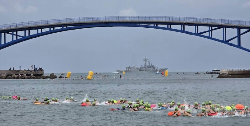 「2026 PENGHU OCEANMAN 國際泳渡澎湖灣」，14日受天候影響，泳渡組5公里改由觀音亭海域下水挑戰，立式划槳5公里在湧浪海潮中挺進，海軍軍艦也在風浪中出勤，場面壯觀。中央社  115年6月14日